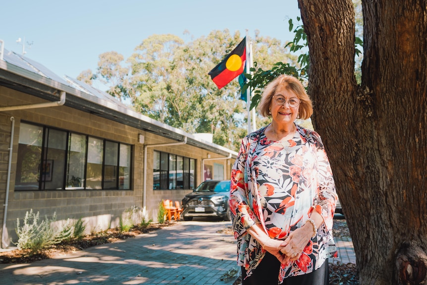 Rhonda is standing next to a tree wearing a colour printed top
