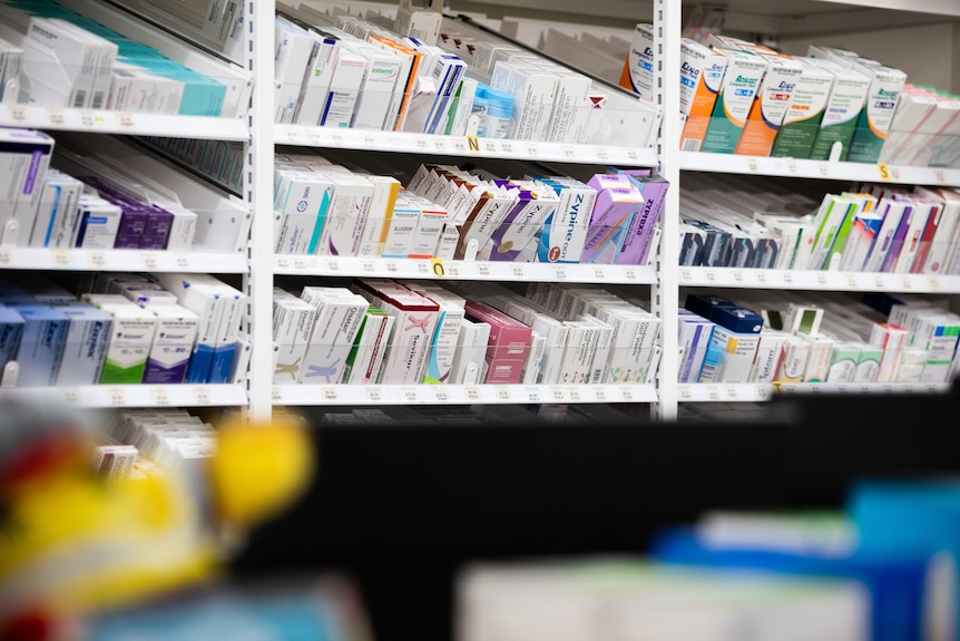A shelf filled with boxes of drugs in a pharmacy.