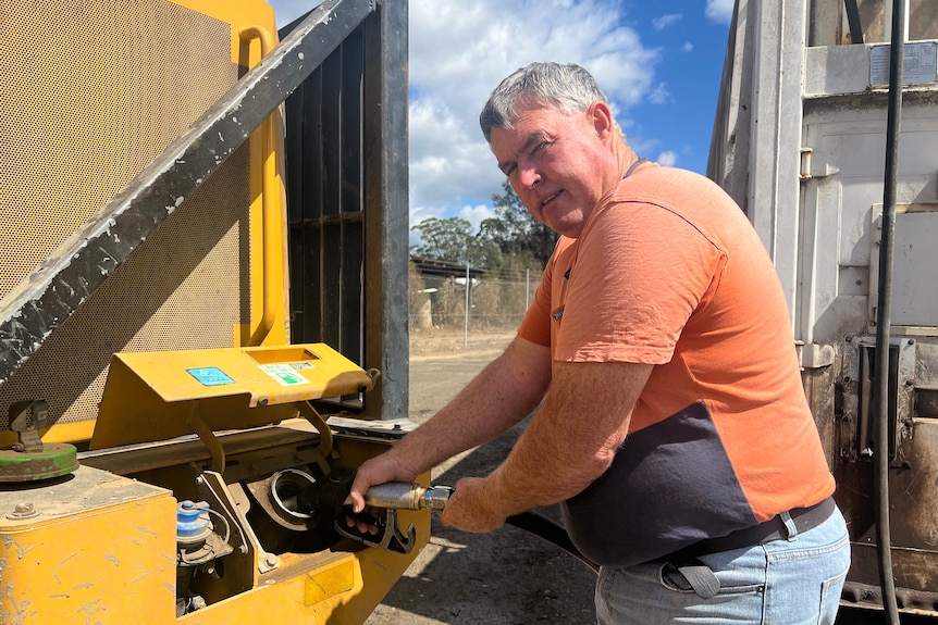 Man pumping fuel into a tractor.