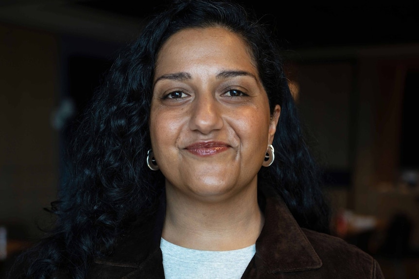 A woman looks at the camera smiling.