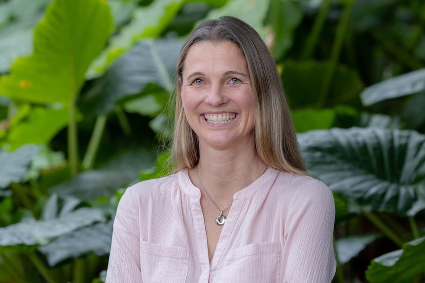 A smiling woman in a garden.