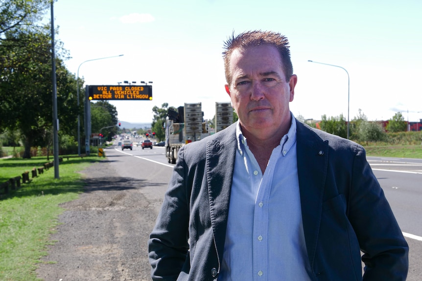 man in suit stands next to road