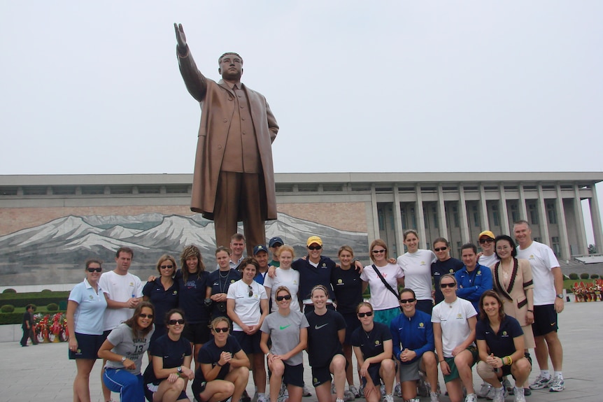 The Matildas pose for a photo in North Korea in front of a statue