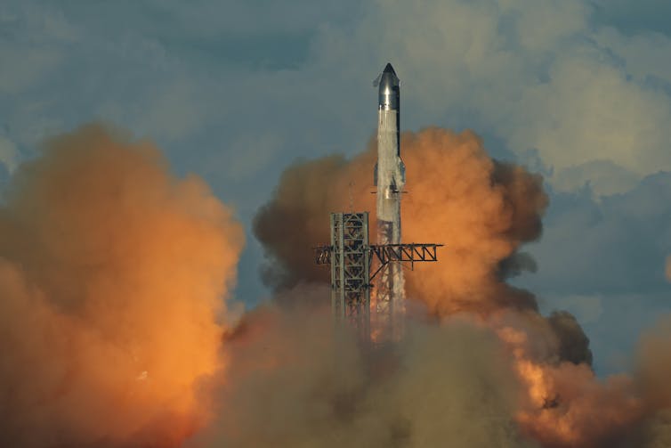 A large rocket launching into the sky, surrounded by plumes of smoke.