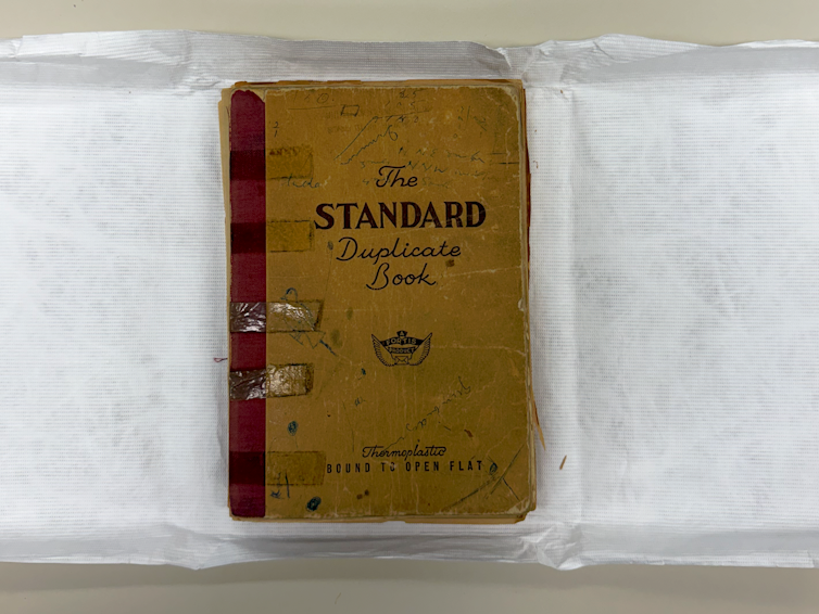 An old notebook with brown cover displayed on archival paper.