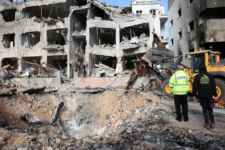 The damaged rubble of a large grey concrete building.