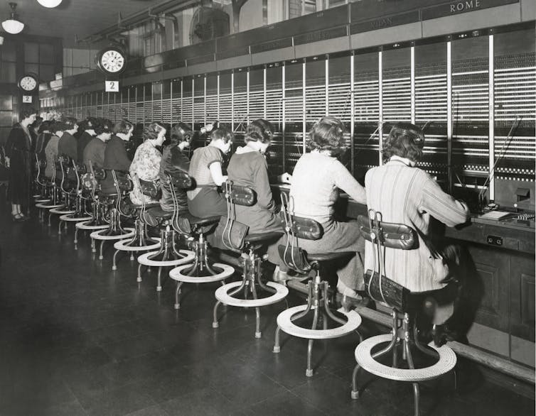 a row of female telephone switchboard operators working in the 1930s.