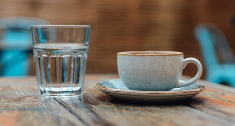 clear glass of water next to white ceramic mug in saucer on table