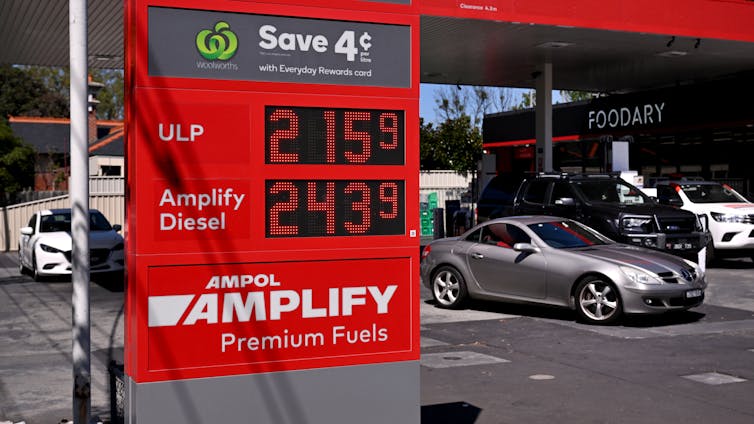 Cars buying fuel at a fuel station, prices seen on a digital display.