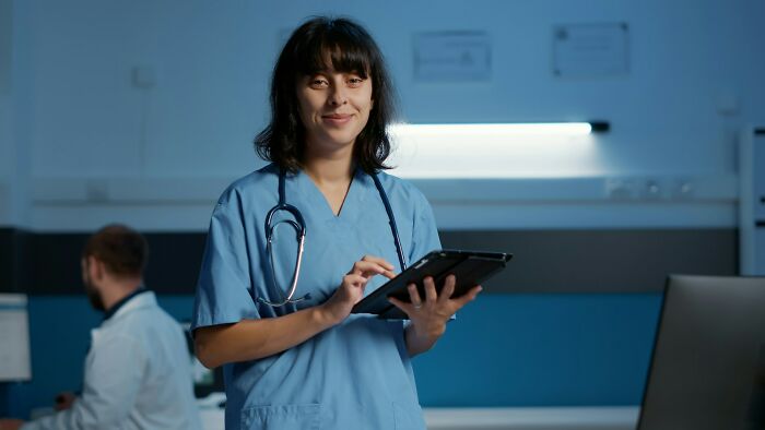 Medical professional in blue scrubs holding a tablet, representing cases of patients faking it in a clinical setting.
