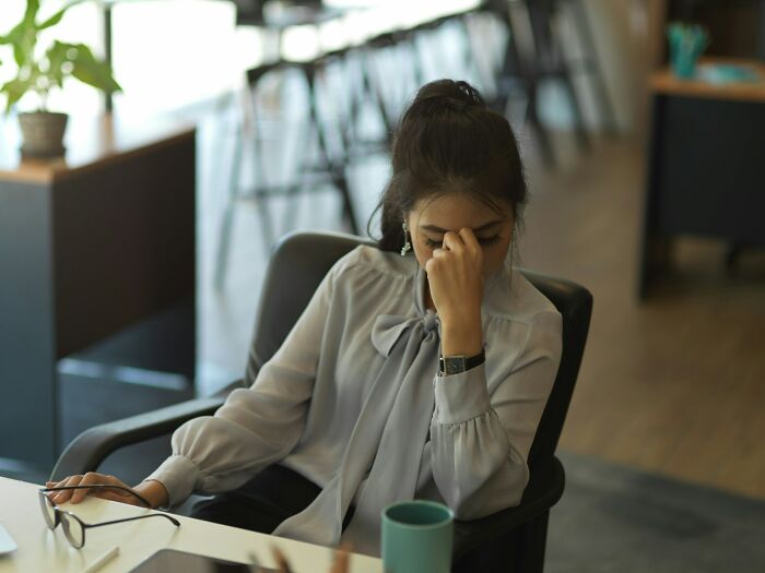 Woman sitting at desk looking stressed, illustrating patients faking it according to medical pros online.