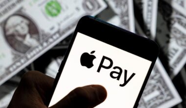 A phone with an Apple Pay logo held over American dollar bills.