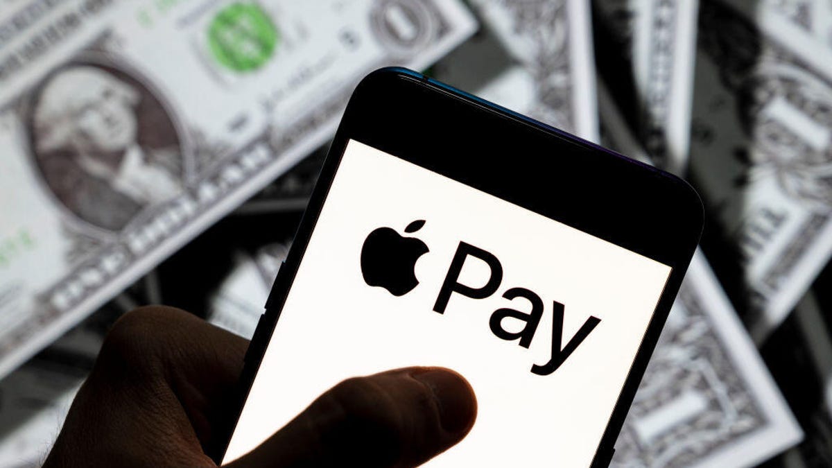A phone with an Apple Pay logo held over American dollar bills.