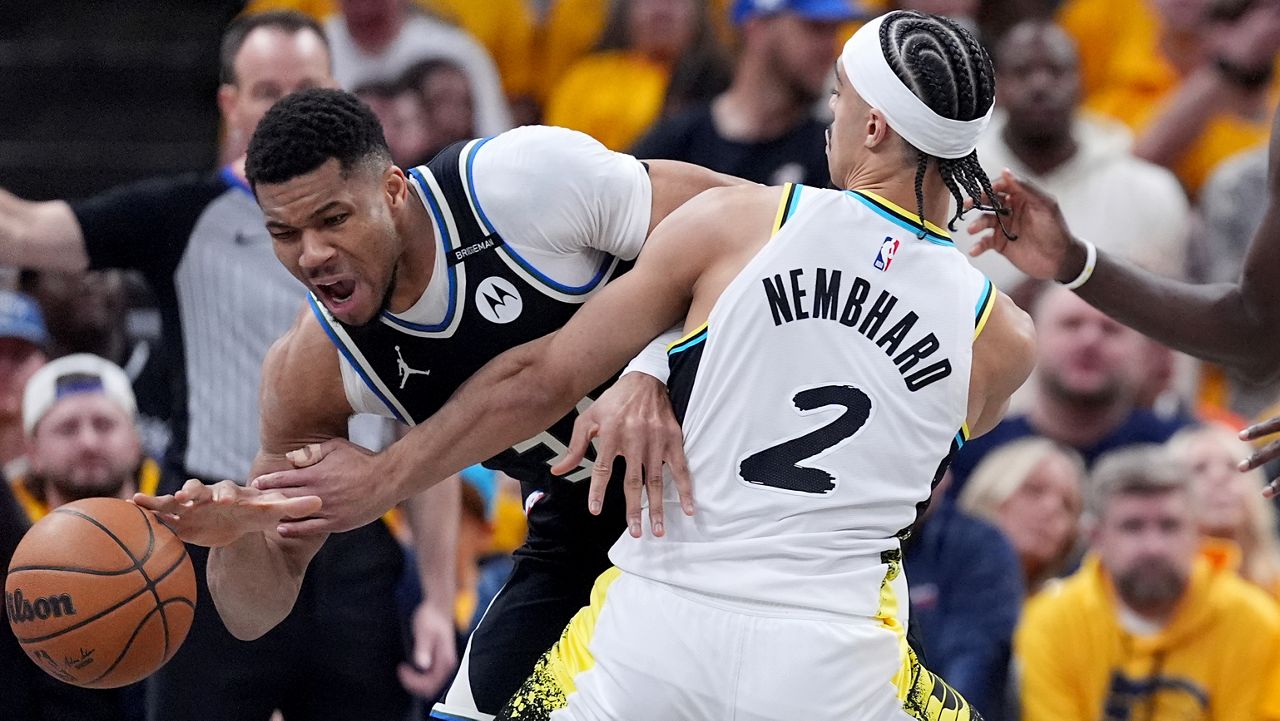 Milwaukee Bucks' Giannis Antetokounmpo, left, dribbles as Indiana Pacers' Andrew Nembhard (2) defends during the first half of a first-round NBA basketball playoff game, Saturday, April 19, 2025, in Indianapolis. (AP Photo/Michael Conroy)
