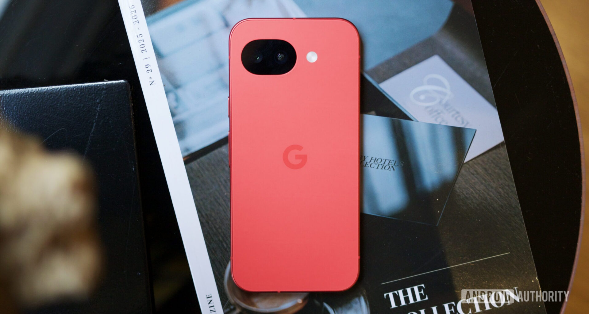 The Berry Google Pixel 10a lying face down on a coffee table.