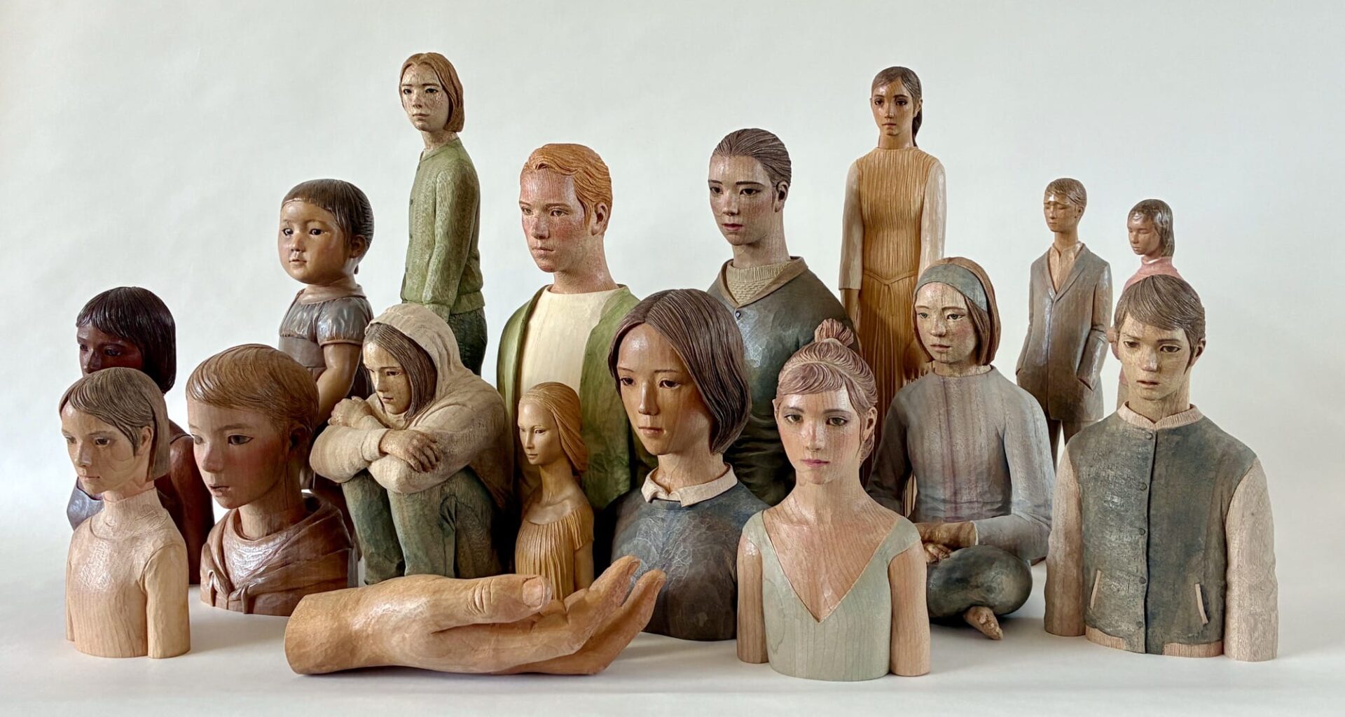a collection of carved wooden figures and a large hand