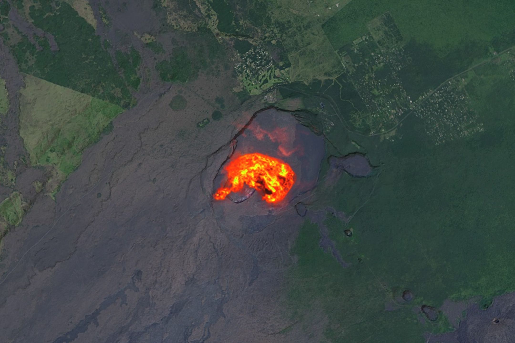 The heat signature from an eruption at Kilauea glows yellow and orange in the volcano’s summit crater.