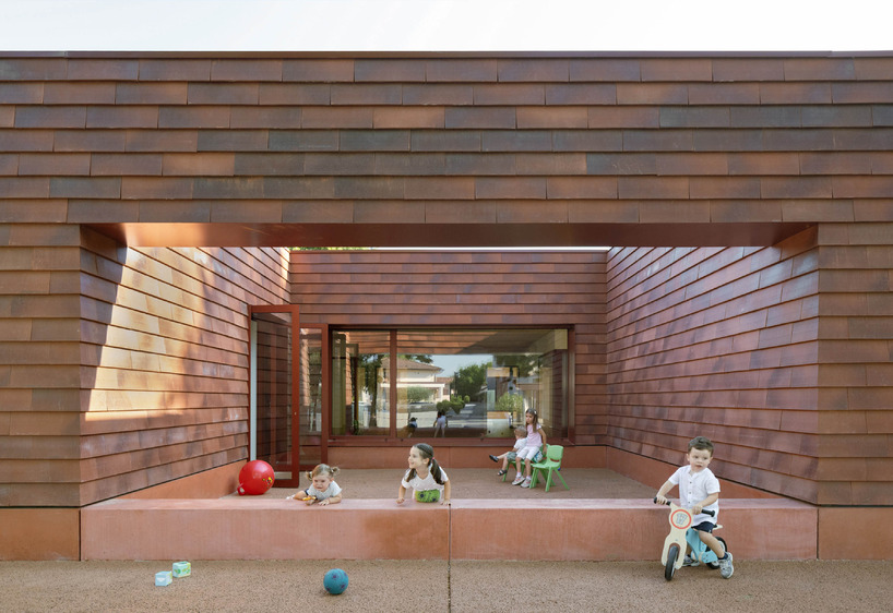 a cluster of terracotta-tiled pyramidal houses envelopes kindergarten in italy - 7