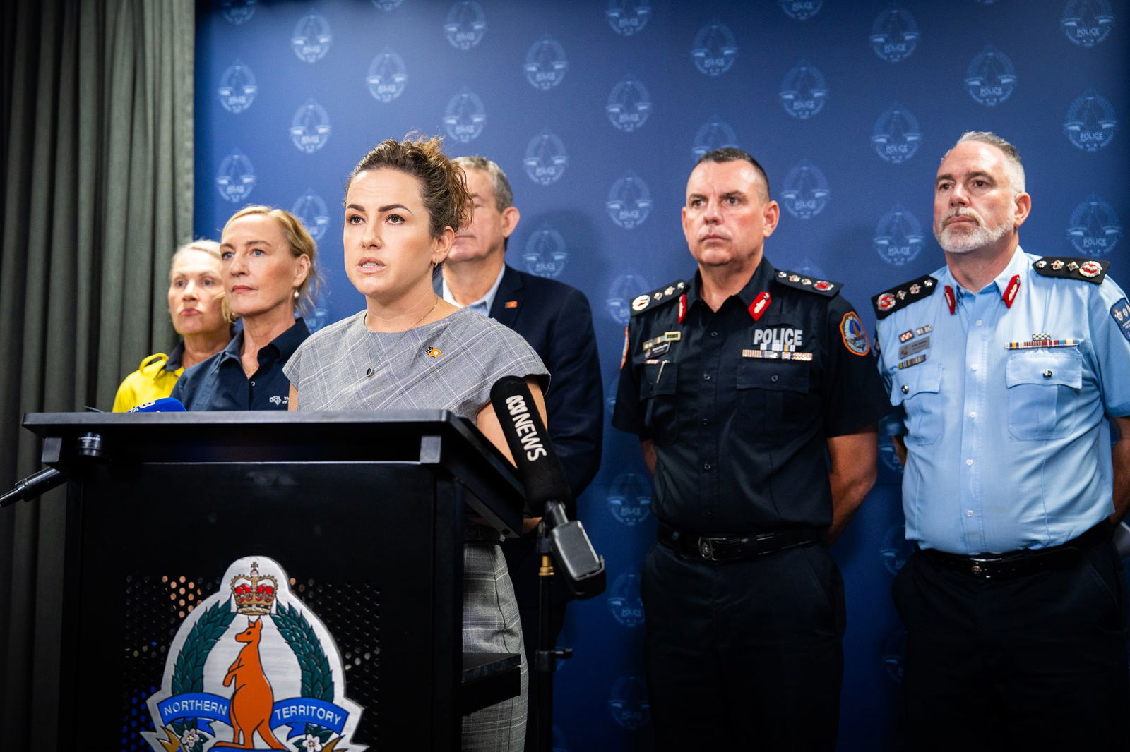 A group of people speaking into microphones at a press conference.