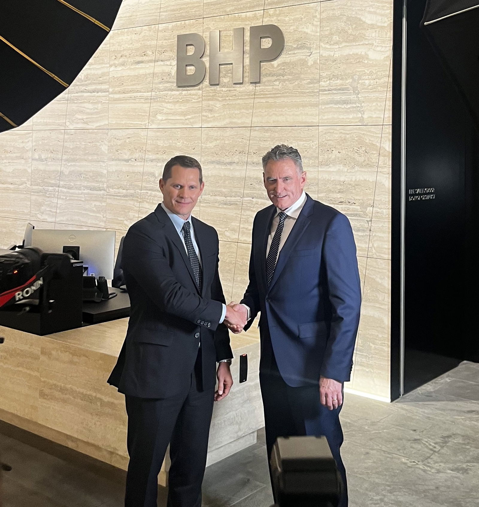 Two Caucasian men in business suits shaking hands in the BHP office, Melbourne.