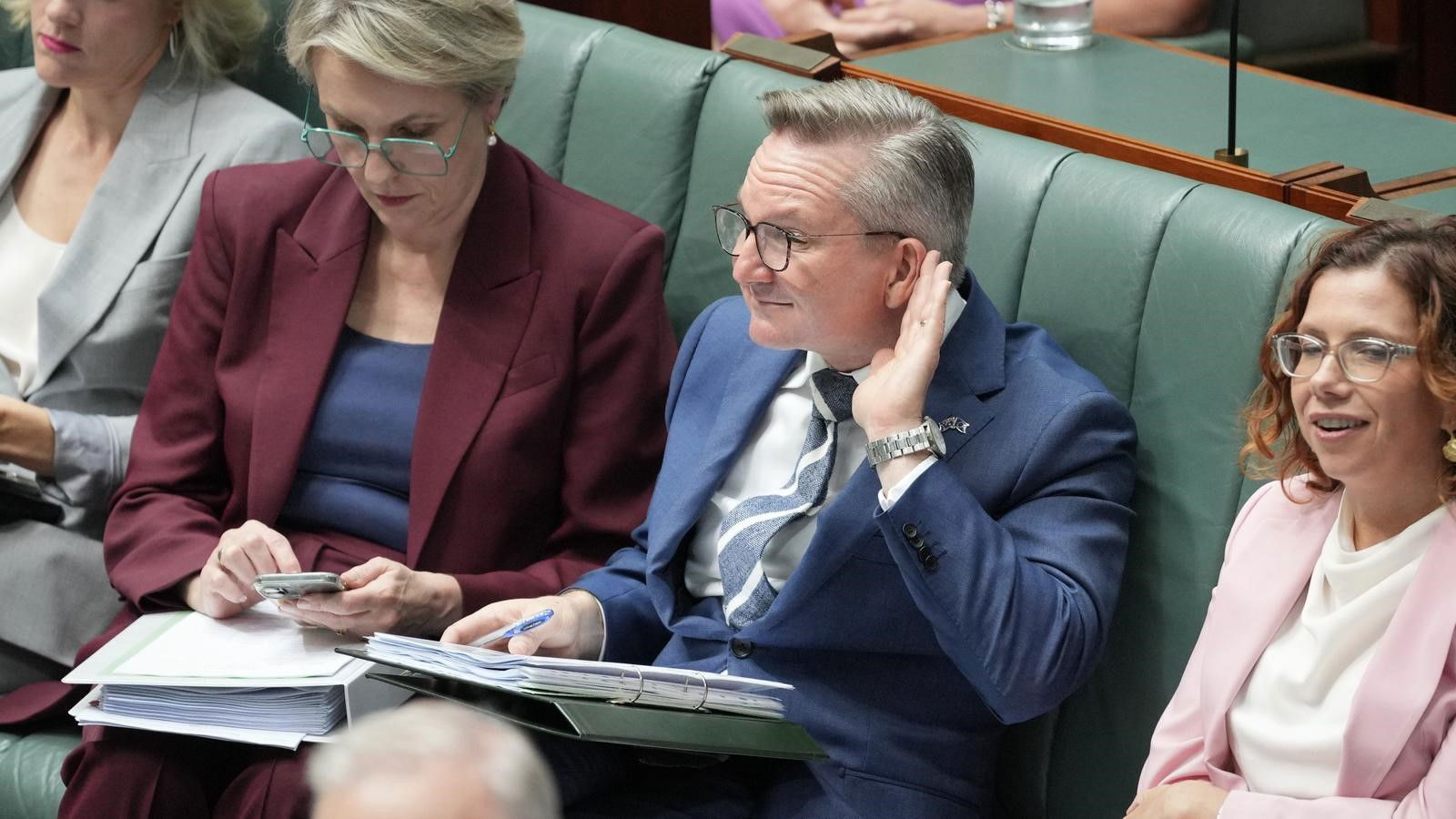 Chris Bowen puts his hand behind his ear as if to say 'I can't hear you' to the Coalition.