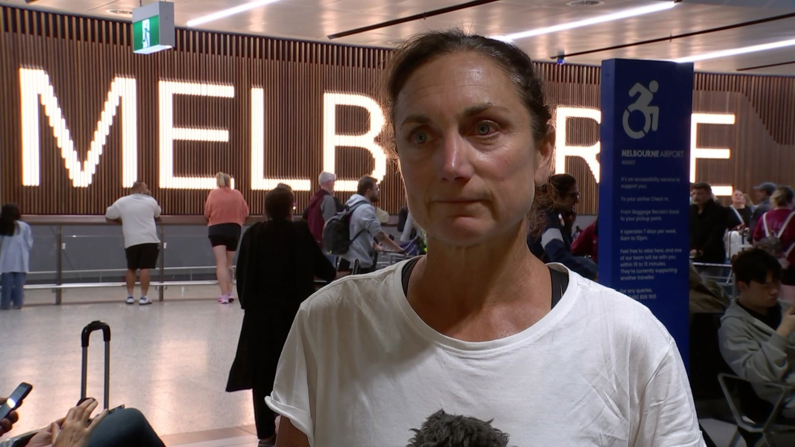 A woman in a white shirt standing in an airport.