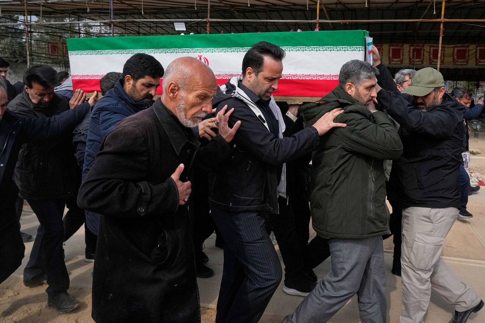 Men carry a coffin, draped in a red, white and green flag.