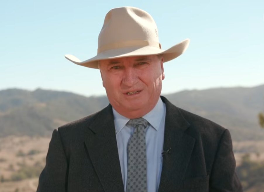 A man in a big hat and suit looks at the camera