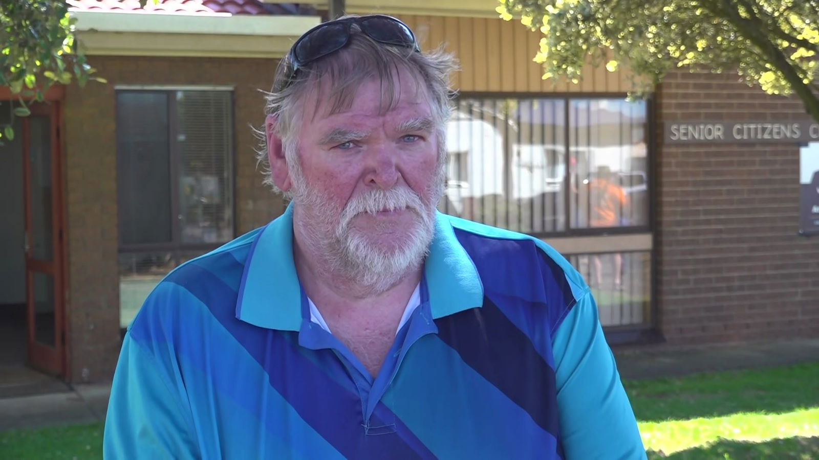 A man in a blue shirt looks at the camera.