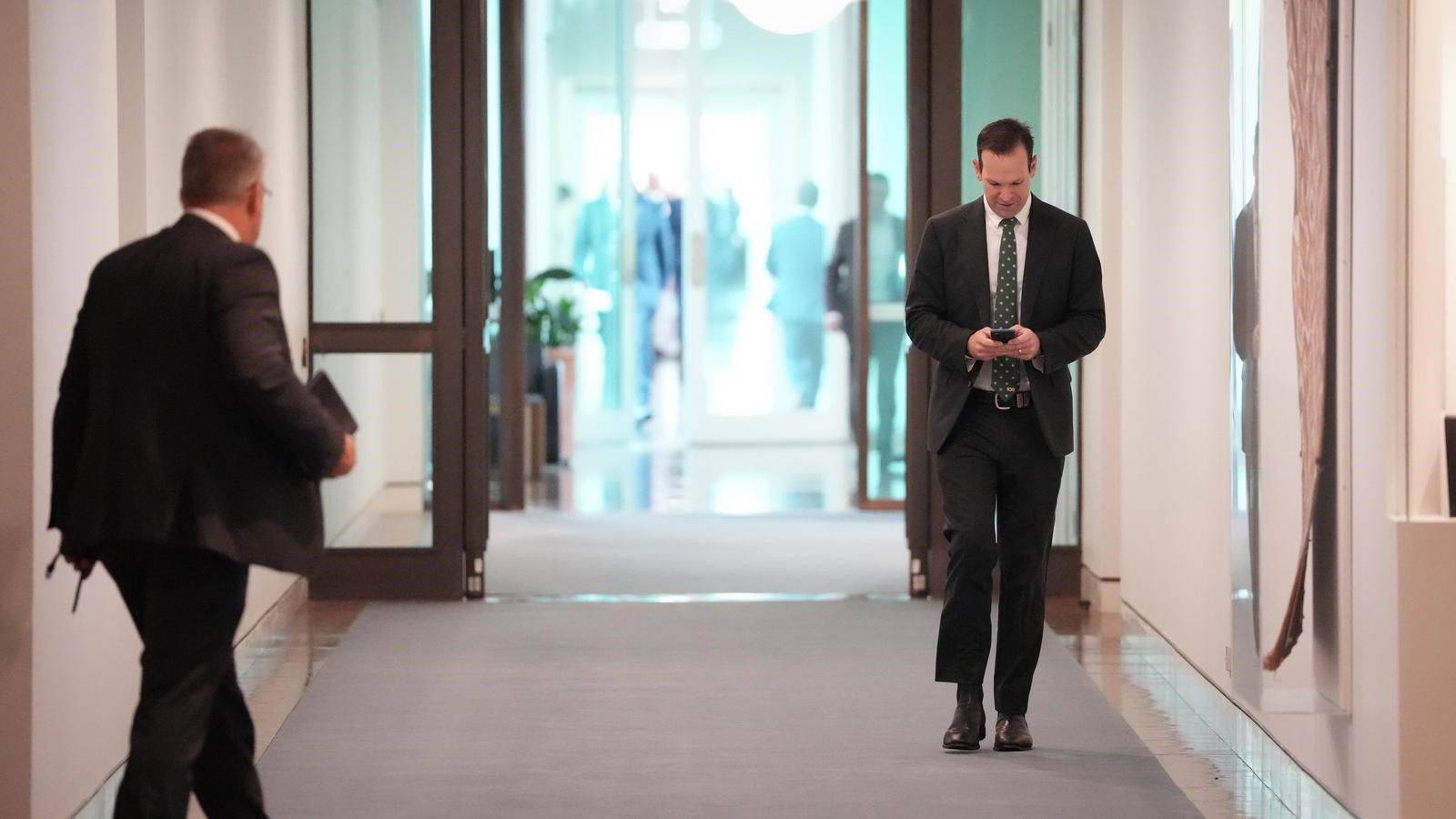 Matt Canavan in the hallway at parliament on his phone