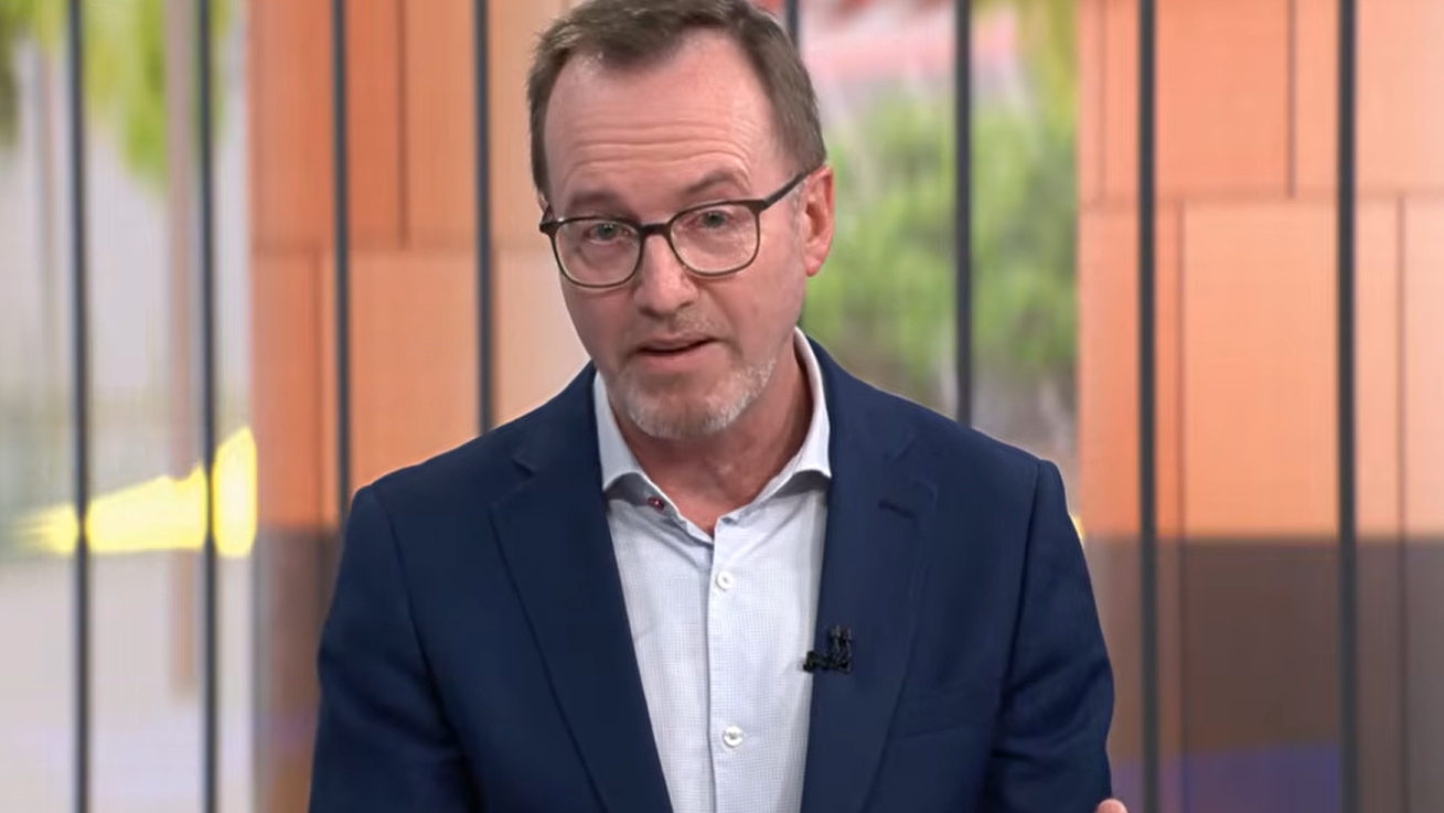 A middle-aged man with glasses looks earnestly at the camera.