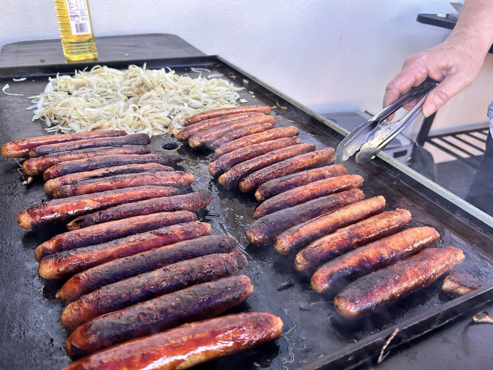 Sausages and onions on a BBQ plate.
