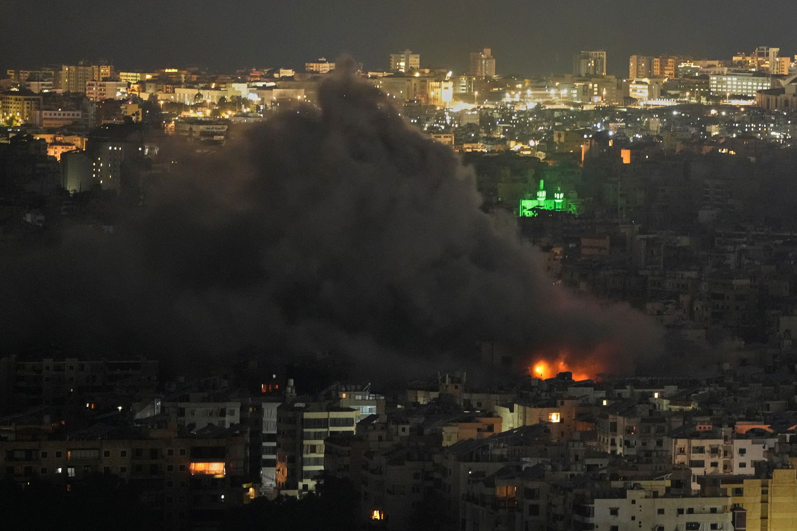 a smoke cloud rises across a city at night