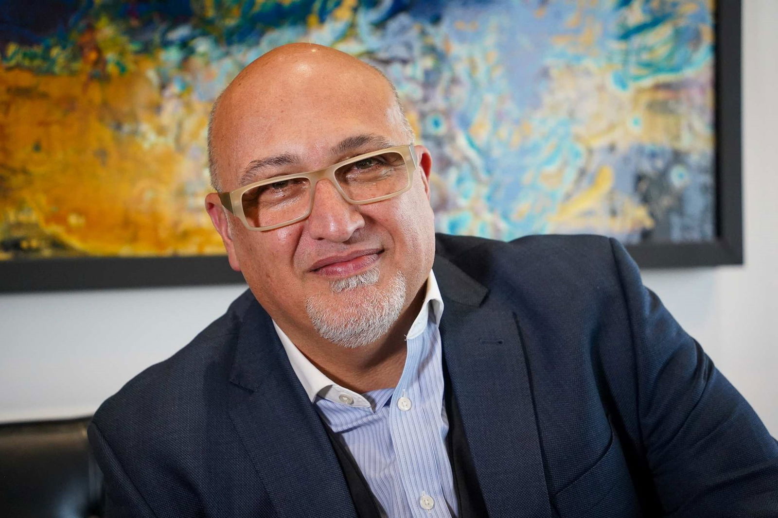 Kambiz Razmara looks at the camera. he wears a suit and beige-rimmed glasses