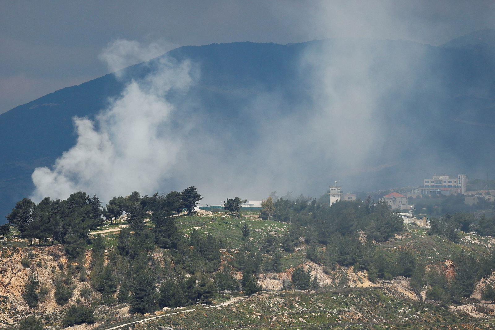 Smoke rises between green mountains