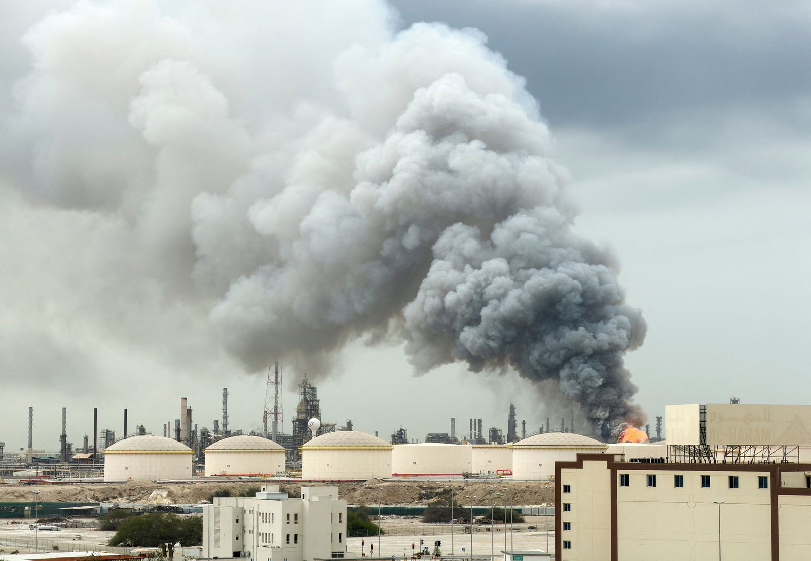 Smoke rises from an oil refinery.