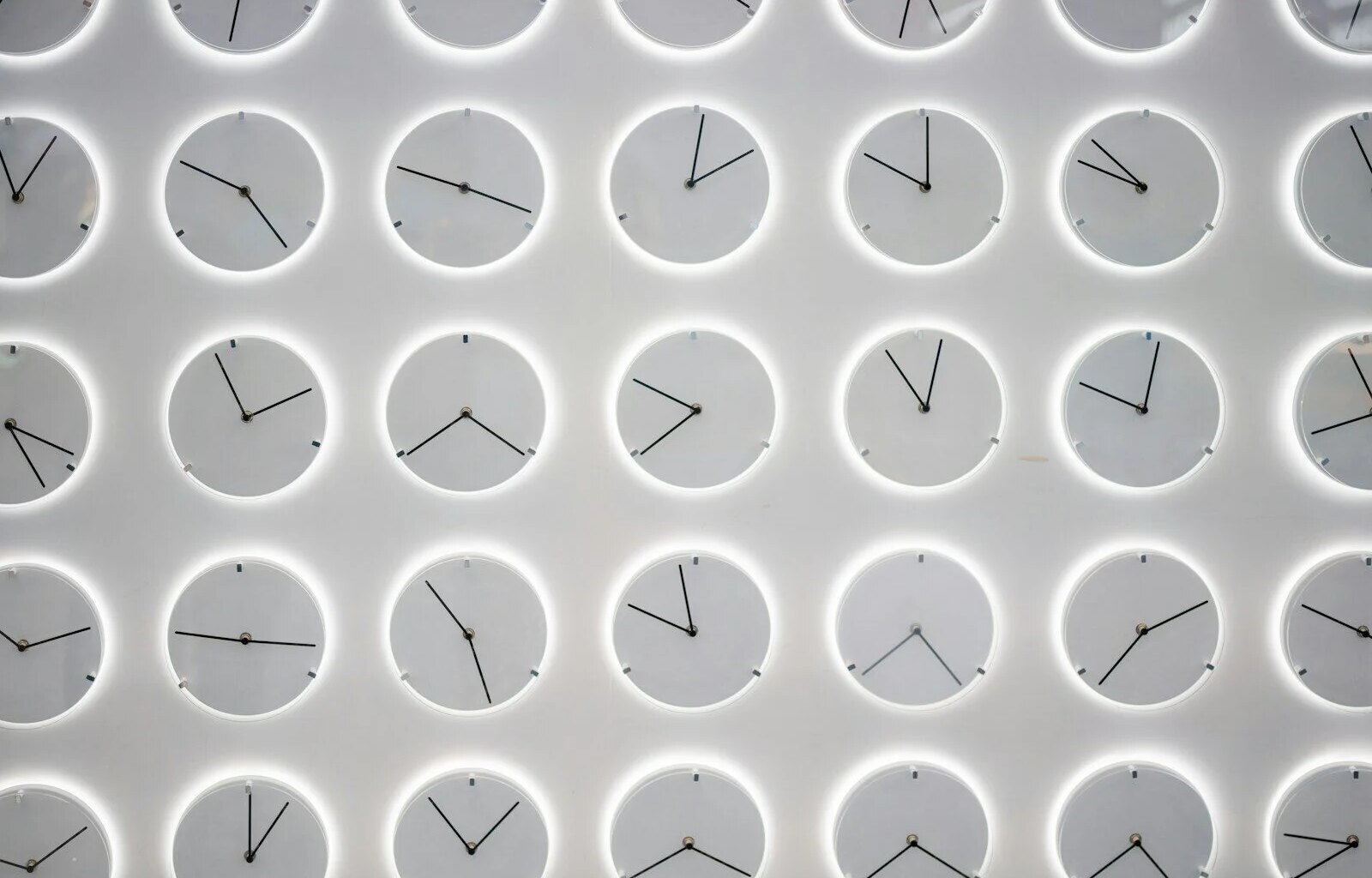 a white wall with many clocks on it