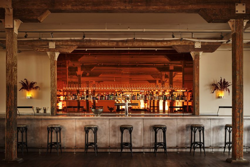 Copper-toned mirror installed behind a long metallic bar counter
