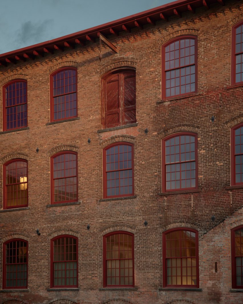 Exterior of a converted brick factory building with large red-framed windows