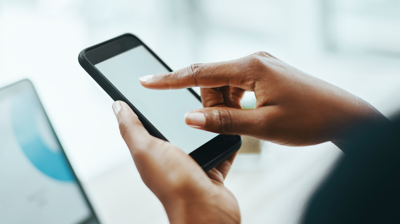 A person touching their smartphone screen with a finger