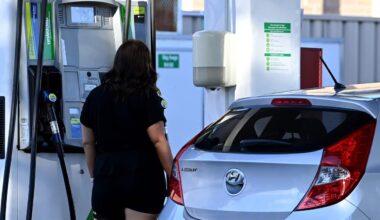 A woman at a petrol pump filling her car with petrol.
