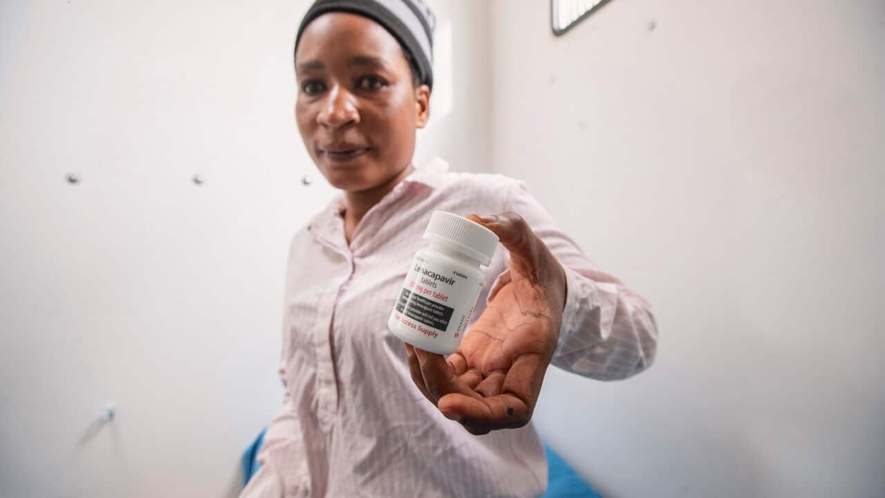 A woman holds a bottle of lenacapavir tablets.