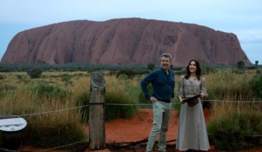 A man and a woman pose for a photo with a red mountain in the background