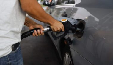 A person fuels up their silver car at a gas station