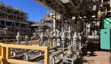 A photo of the Barrow Island natural gas plant in Western Australia. It is a maze of silver pipework against a bright blue sky.