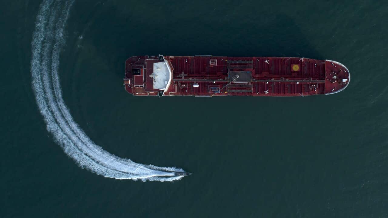 A large vessel and a much smaller boat in the ocean.