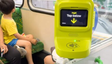 A Myki card reader with a child sitting on a seat behind.