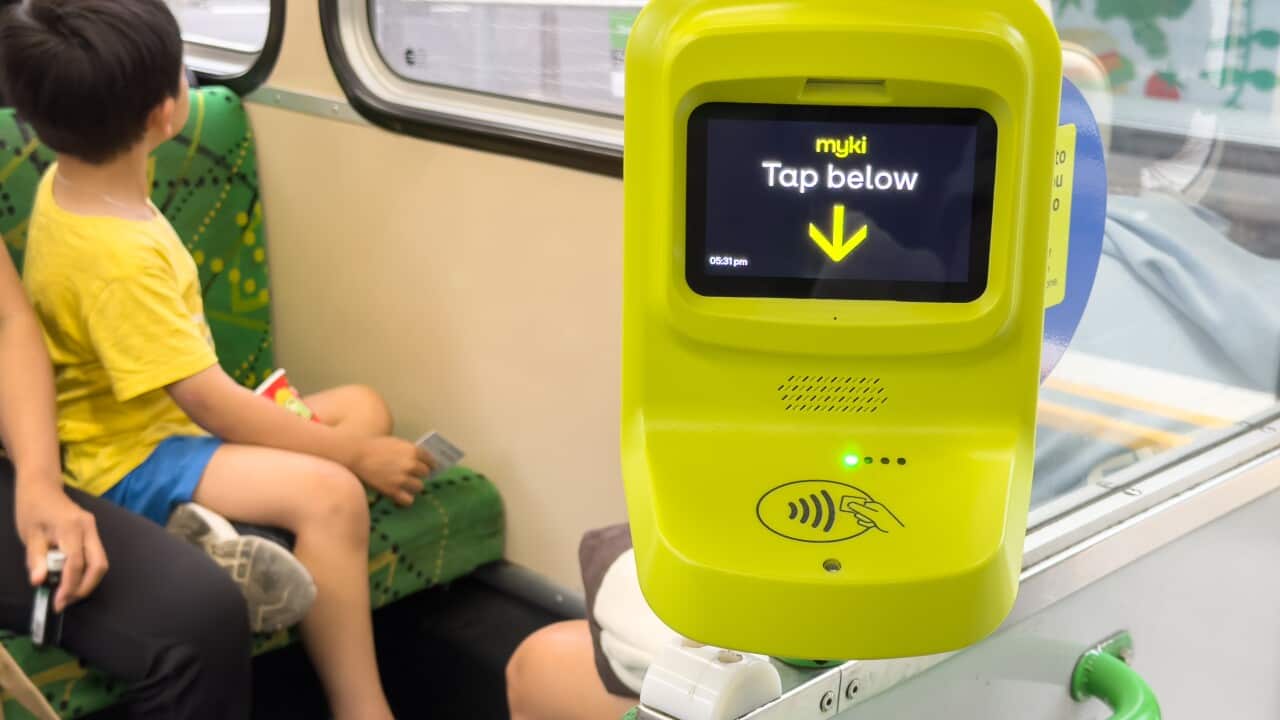 A Myki card reader with a child sitting on a seat behind.