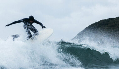 Surfer riding a wave in a Finisterre wetsuit