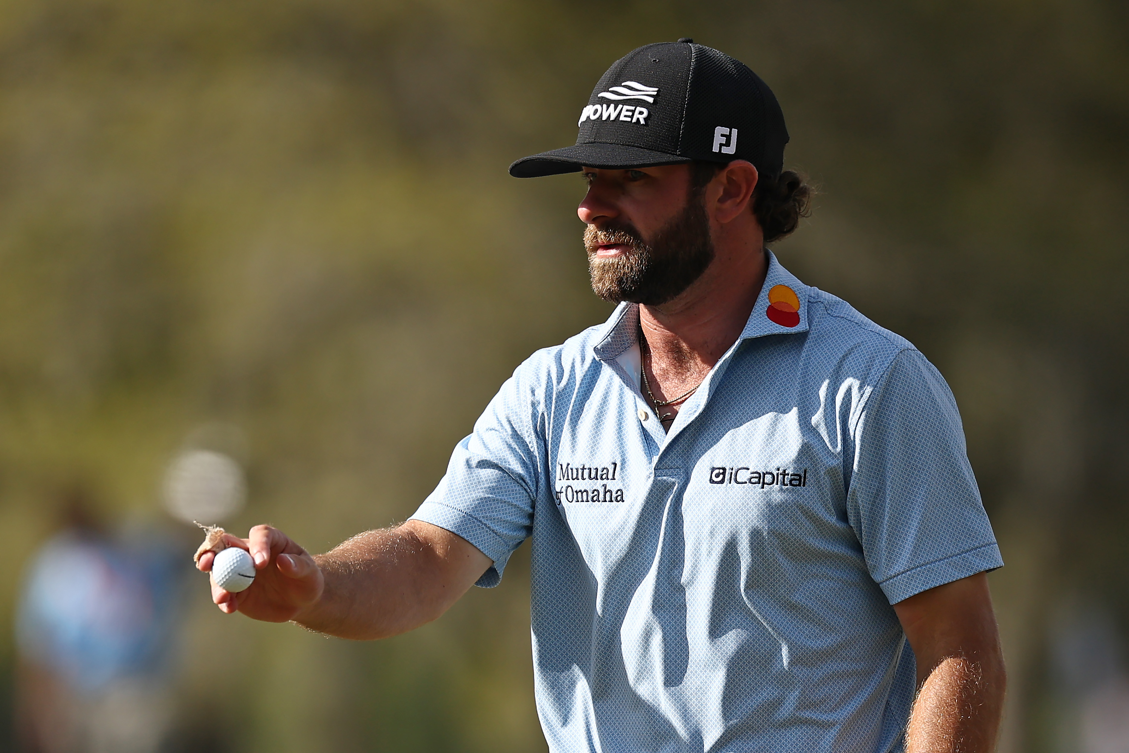 Cameron Young waves to the crowd holding a golf ball